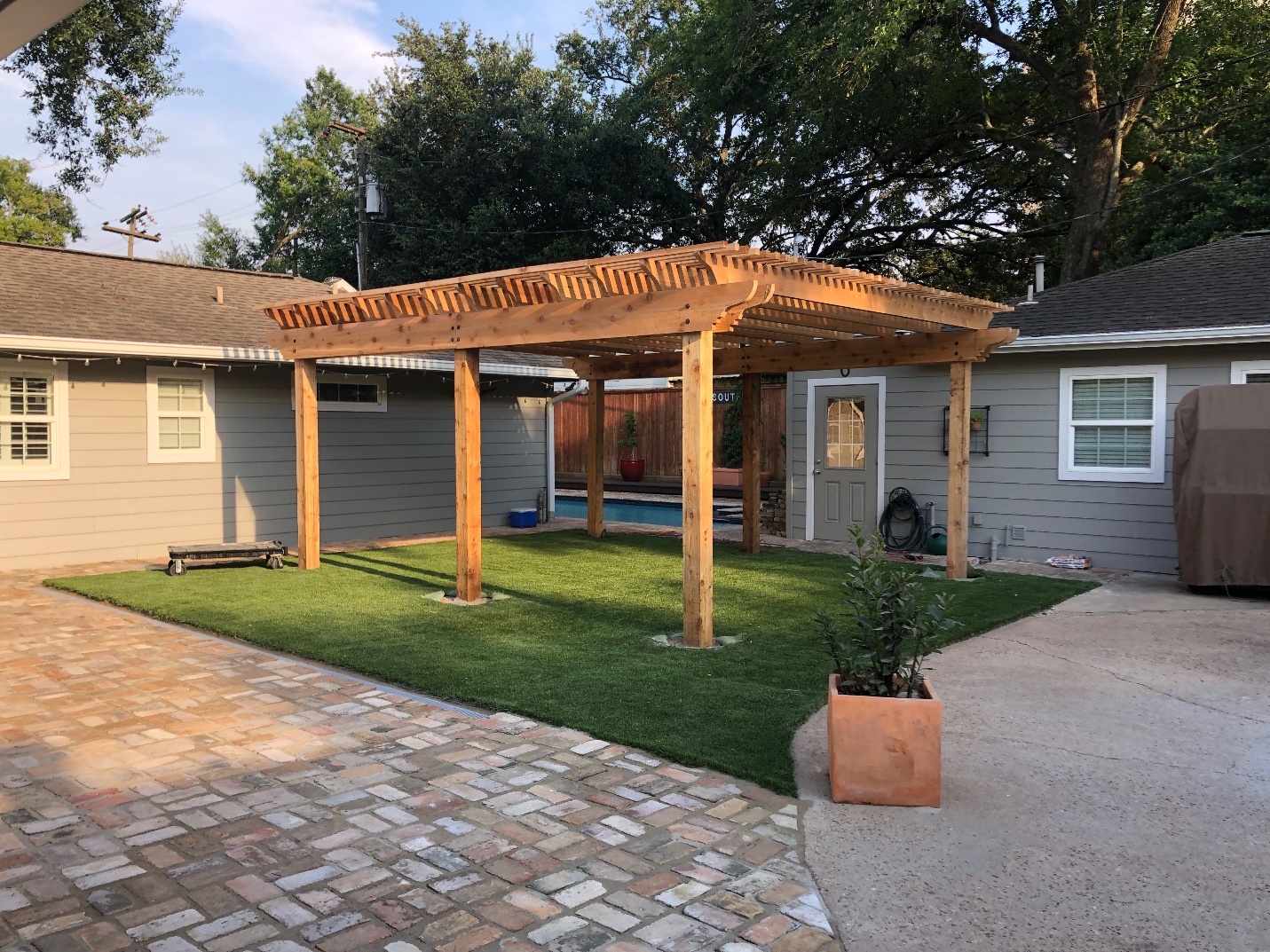 Wooden arbor beside a home and landscaped backyard